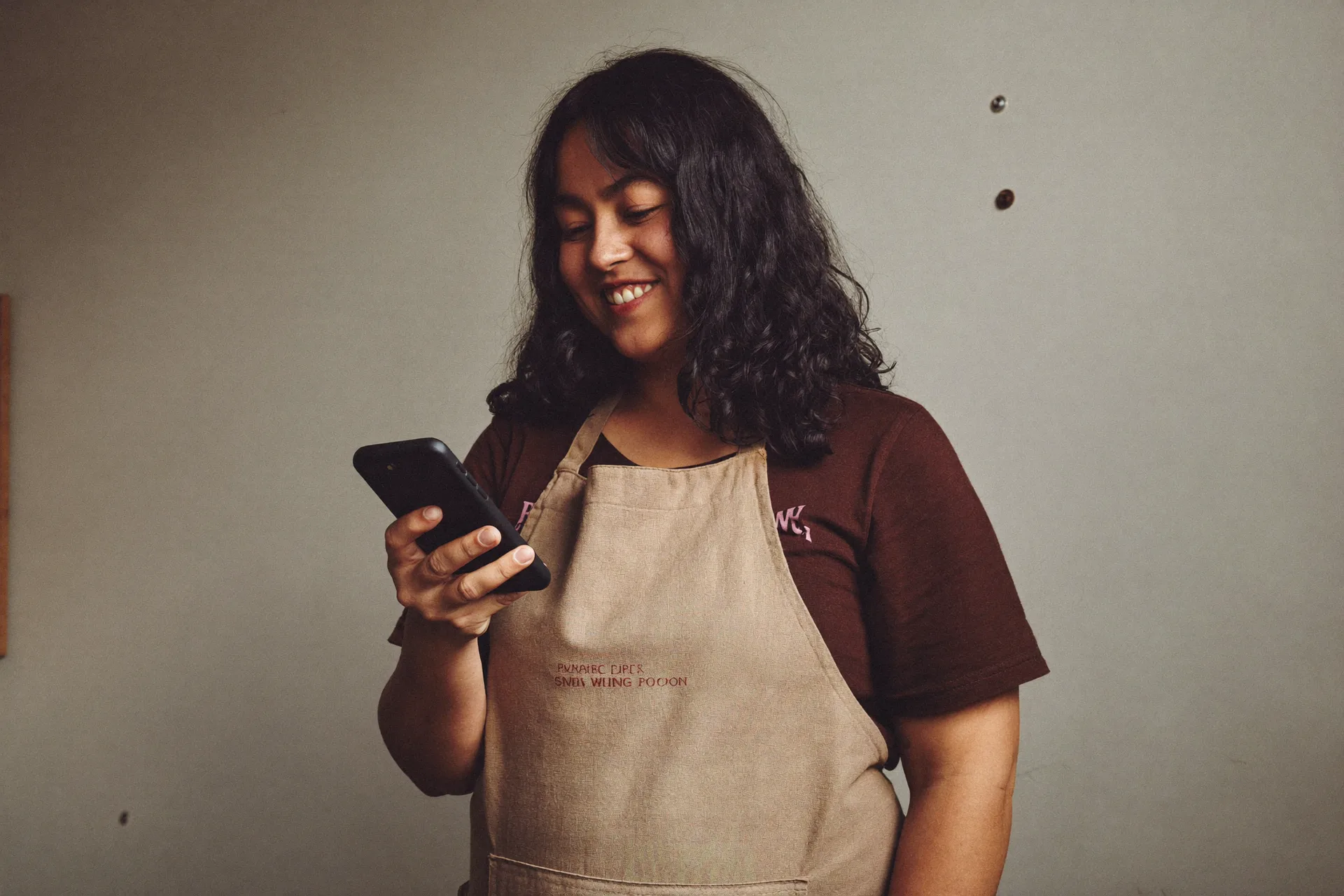 Workshop owner glancing at her phone mid-task